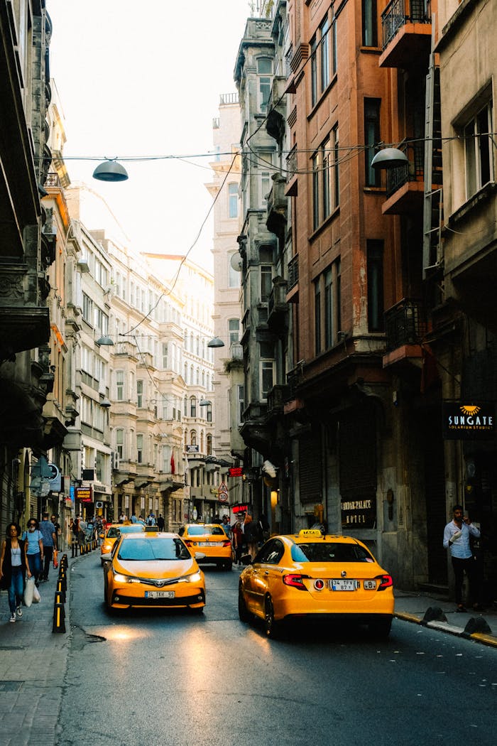 Street scene with yellow taxis and pedestrians in an urban setting, capturing city life and architecture.