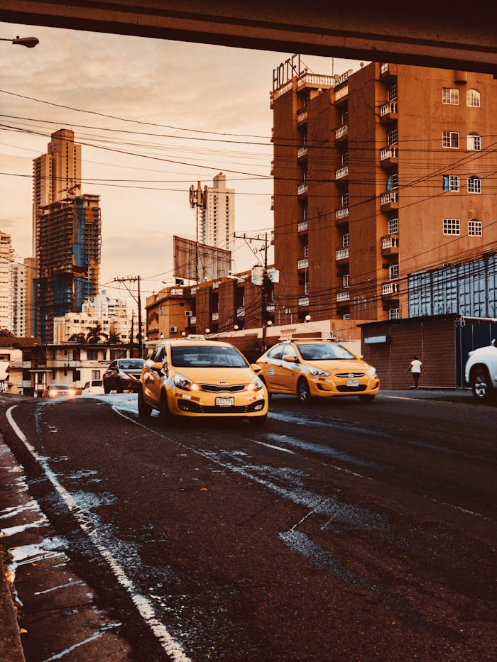 Dynamic cityscape featuring yellow taxis driving through a downtown street with high-rise buildings.