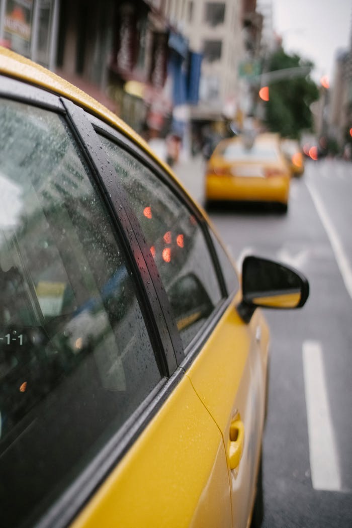 A rainy day city scene with yellow taxis on a busy urban street, showcasing reflections and motion.